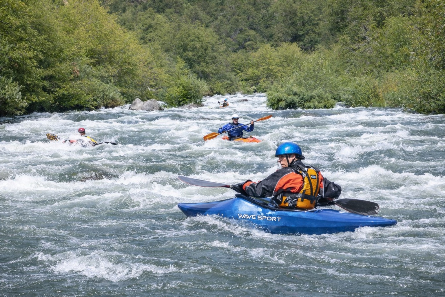 Four kayakers descending continuous rapid.