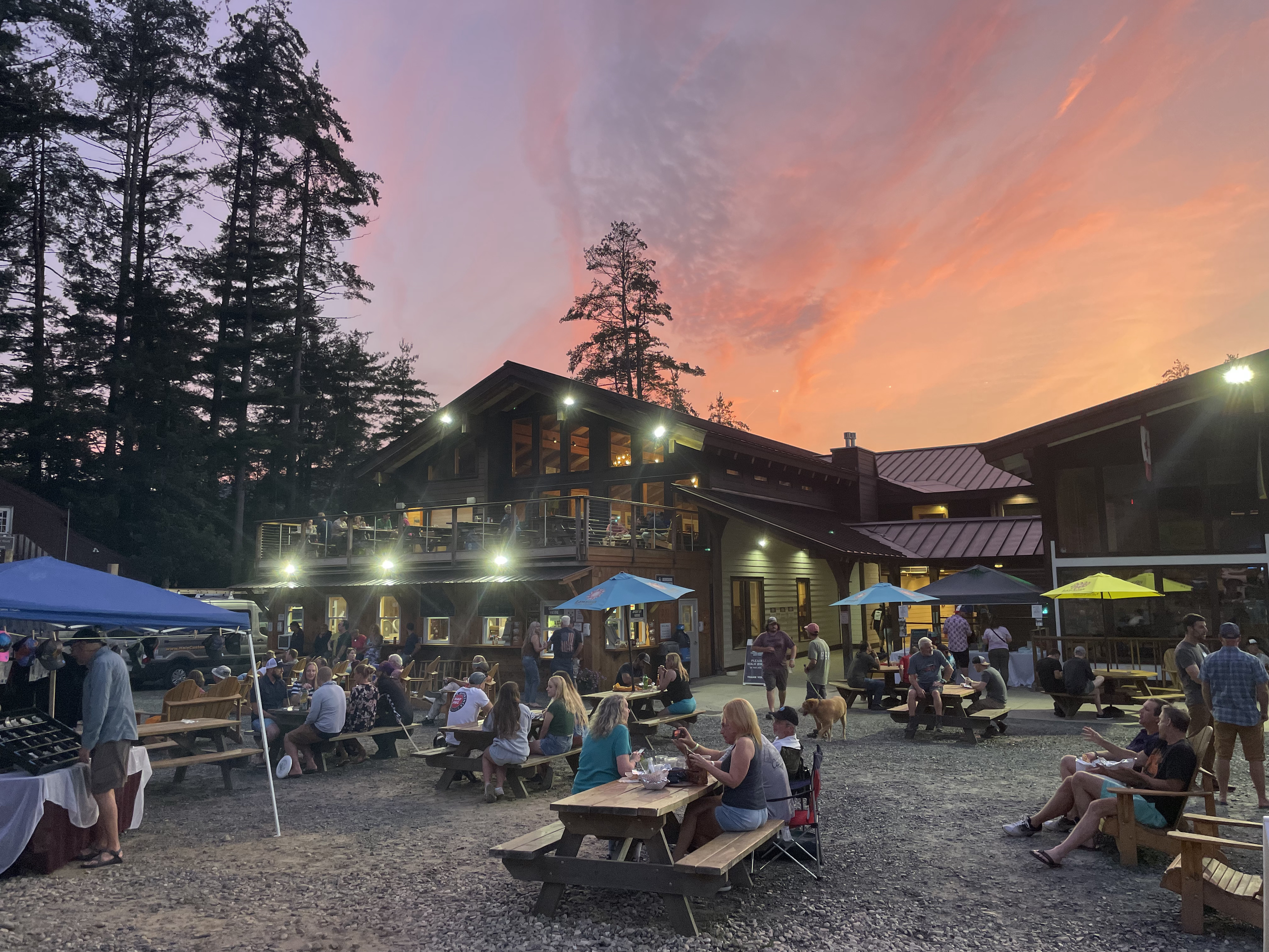 People sitting at tables and gathered at the Deefield Festival site at Berkshire East.