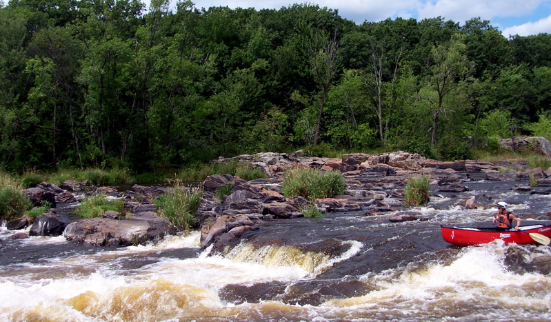 Whitewater canoeist paddling through rapids during a Jim Falls Hydroelectric Project release on the Chippewa River in Wisconsin.